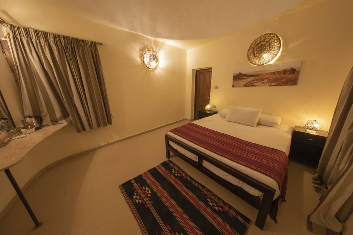 Une chambre à coucher comprenant un lit, une table de chevet, une commode et un luminaire fixé au mur.