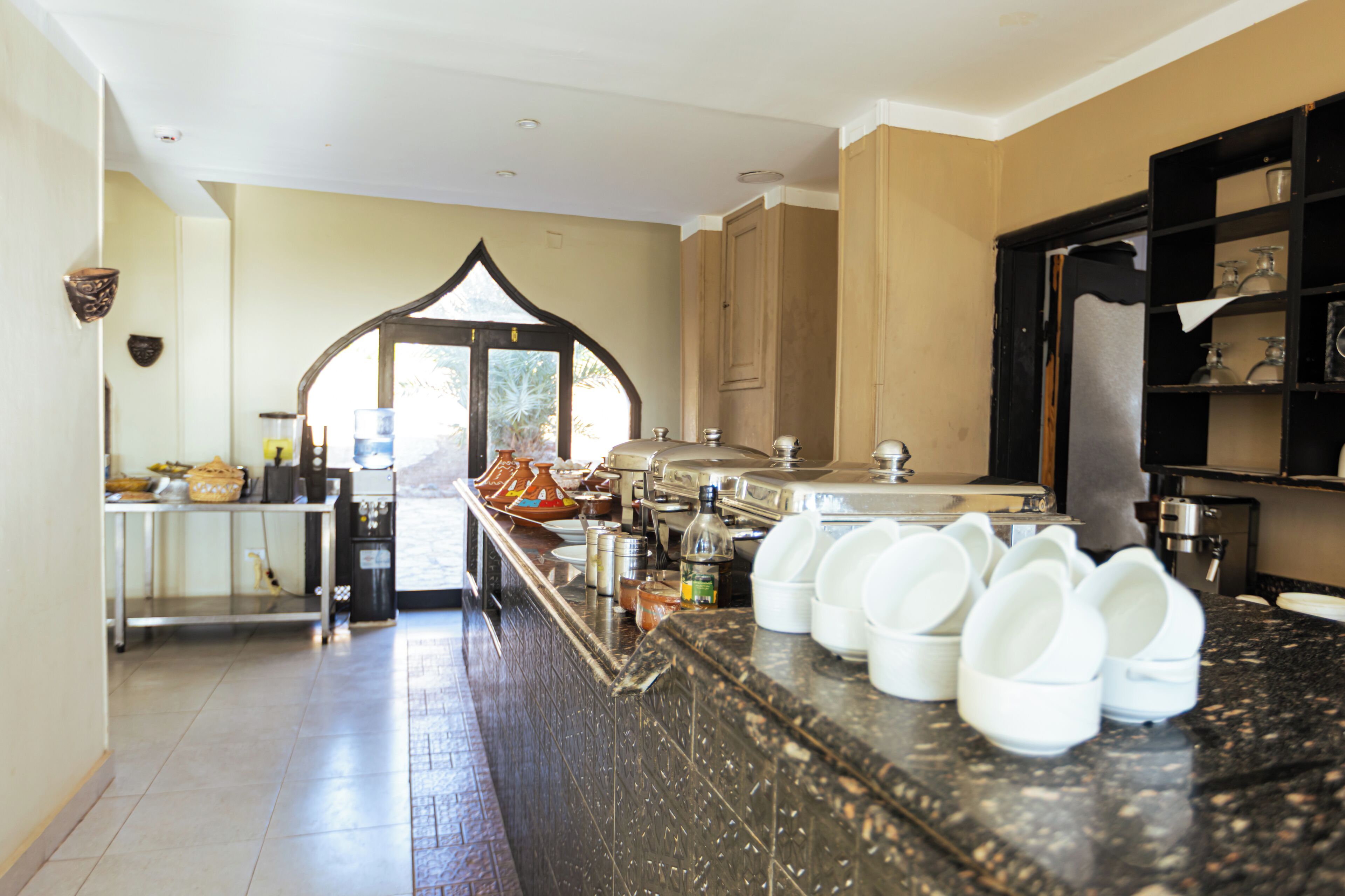 A kitchen with a marble countertop, a coffee machine, and a view of the outdoors.