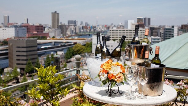 Une table avec des bouteilles de vin et des verres, un arrangement floral et, en arrière-plan, une vue sur la ville.