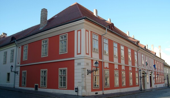 A historic building with a red facade and white trim, featuring multiple windows and a traditional roof. - St. George Residence All Suite Hotel Deluxe (Budapest)