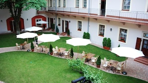 A courtyard with outdoor seating, a tree, and a building with multiple windows and balconies. - St. George Residence All Suite Hotel Deluxe (Budapest)
