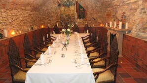 A long dining table set for a meal in a room with stone walls and wooden chairs. - St. George Residence All Suite Hotel Deluxe (Budapest)