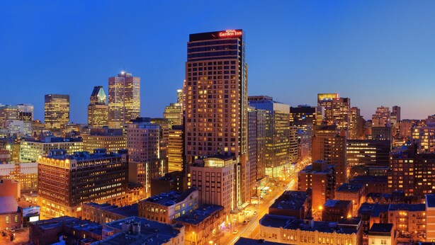 A cityscape at dusk with illuminated buildings, including a prominent Hilton Garden Inn. - Hilton Garden Inn Montréal Centre-ville (Montreal)