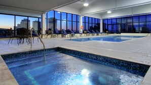 A swimming pool with lounge chairs and a city view at dusk. - Hilton Garden Inn Montréal Centre-ville (Montreal)