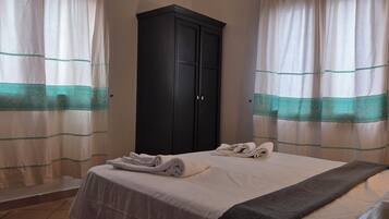 A hotel room with a bed, a dark wardrobe, and curtains with a teal pattern.