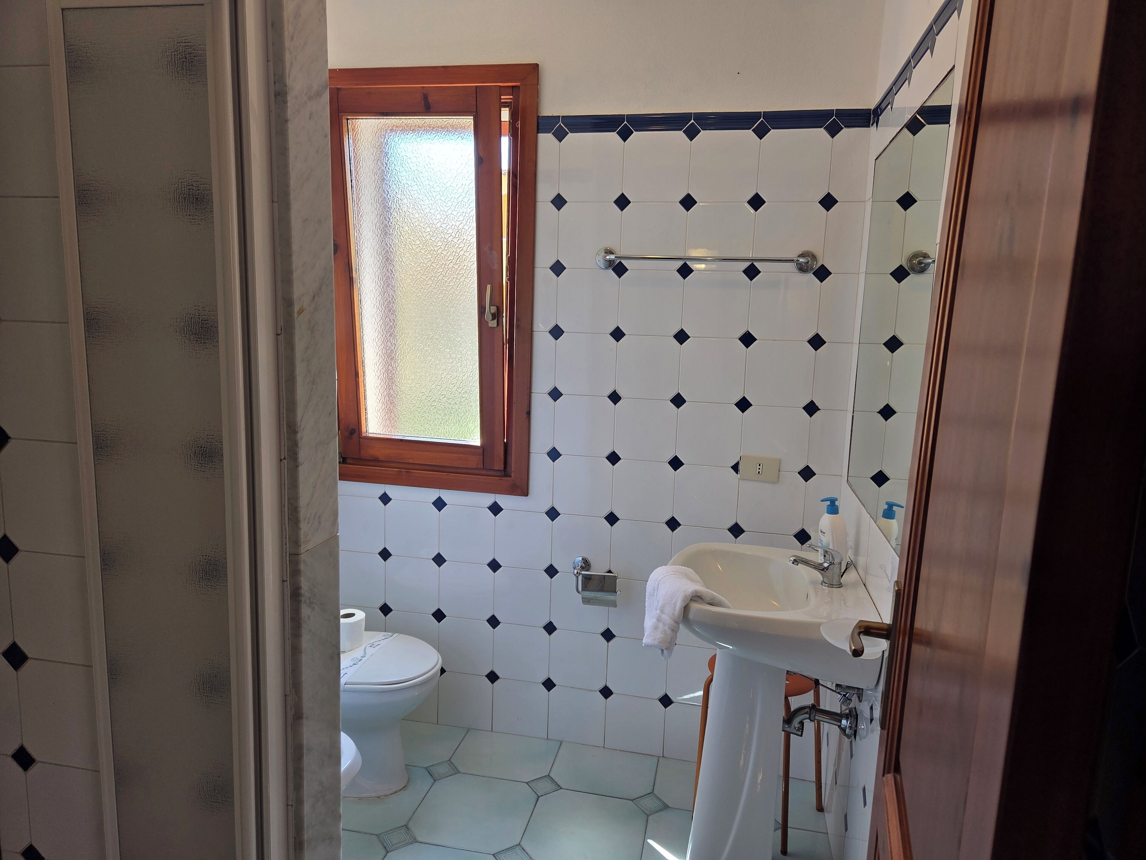 A bathroom with a toilet, sink, and window.
