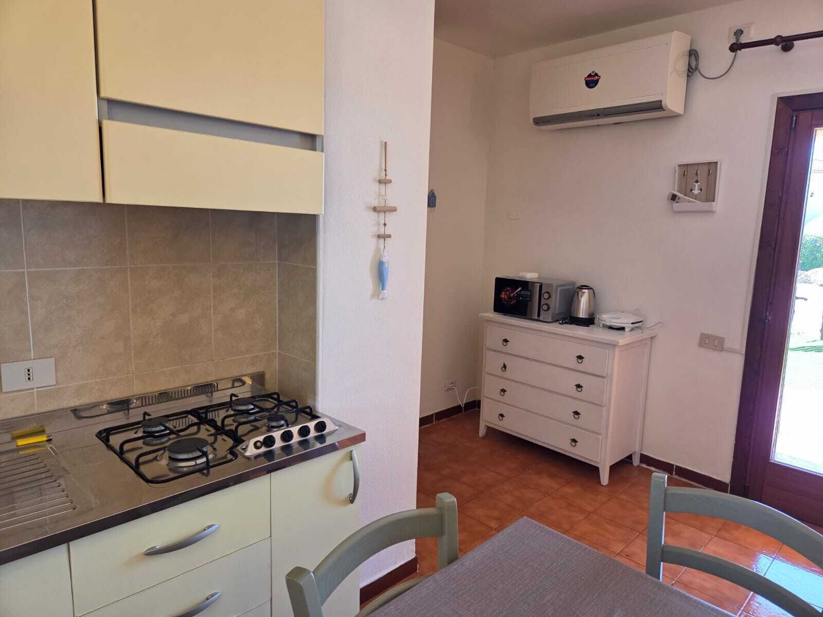 Una cocina compacta con estufa a gas, microondas y un mueble pequeño.