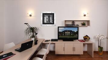 Uma sala de estar moderna com uma escrivaninha de madeira, um laptop, uma televisão e um vaso de planta.