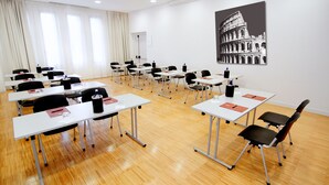 A conference room with white tables, black chairs, and a large black-and-white photo of the Colosseum on the wall. - Euro Hotel Residence (Concorezzo)