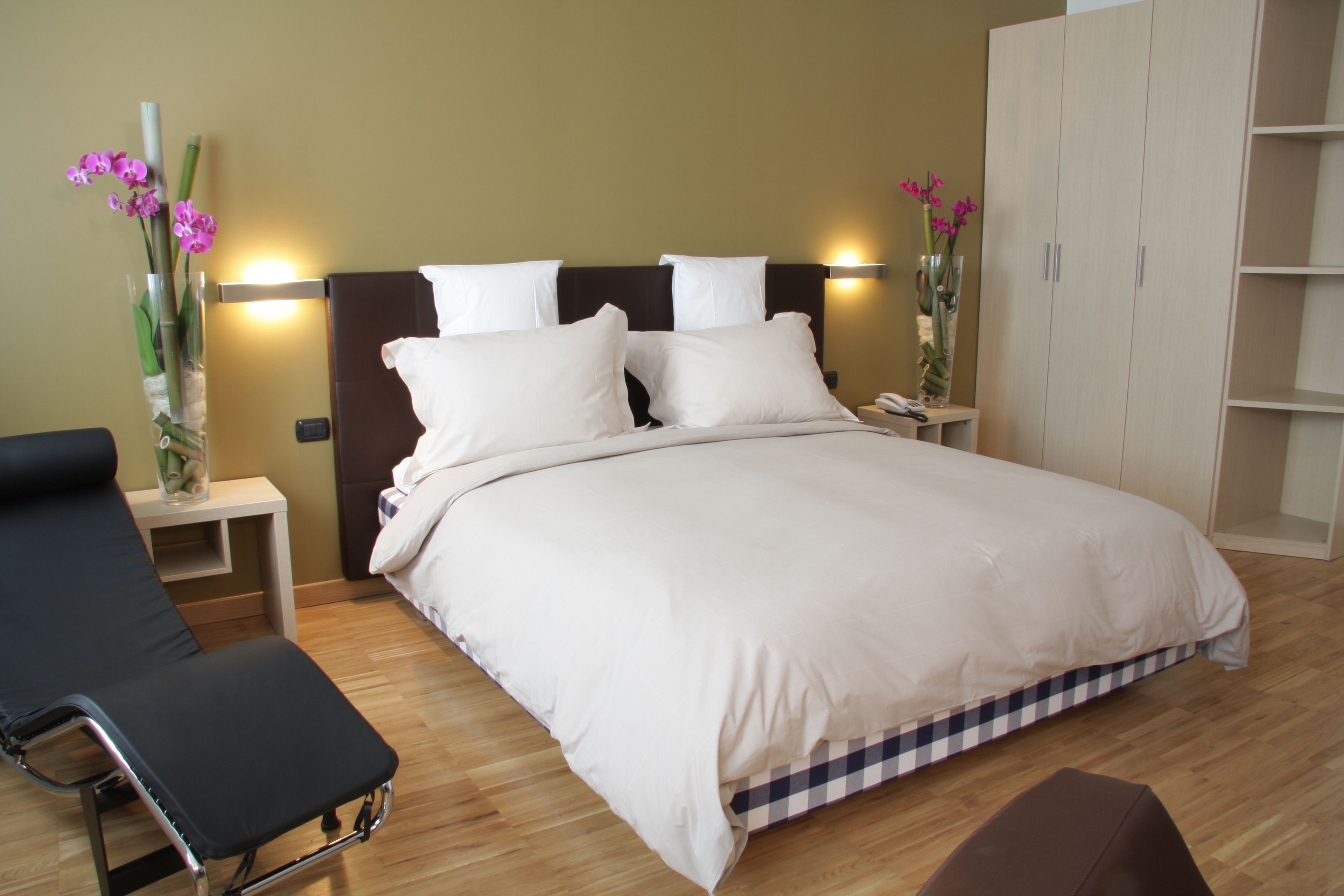 Une chambre d’hôtel avec un grand lit, des tables de chevet, une chaise et une armoire.