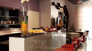 A modern bar area with a long counter, multiple stools, and a variety of bottles on shelves. - Euro Hotel Residence (Concorezzo)