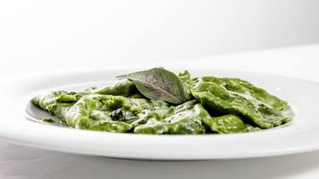 Un plato de pasta verde con una decoración de hoja sobre un plato blanco.