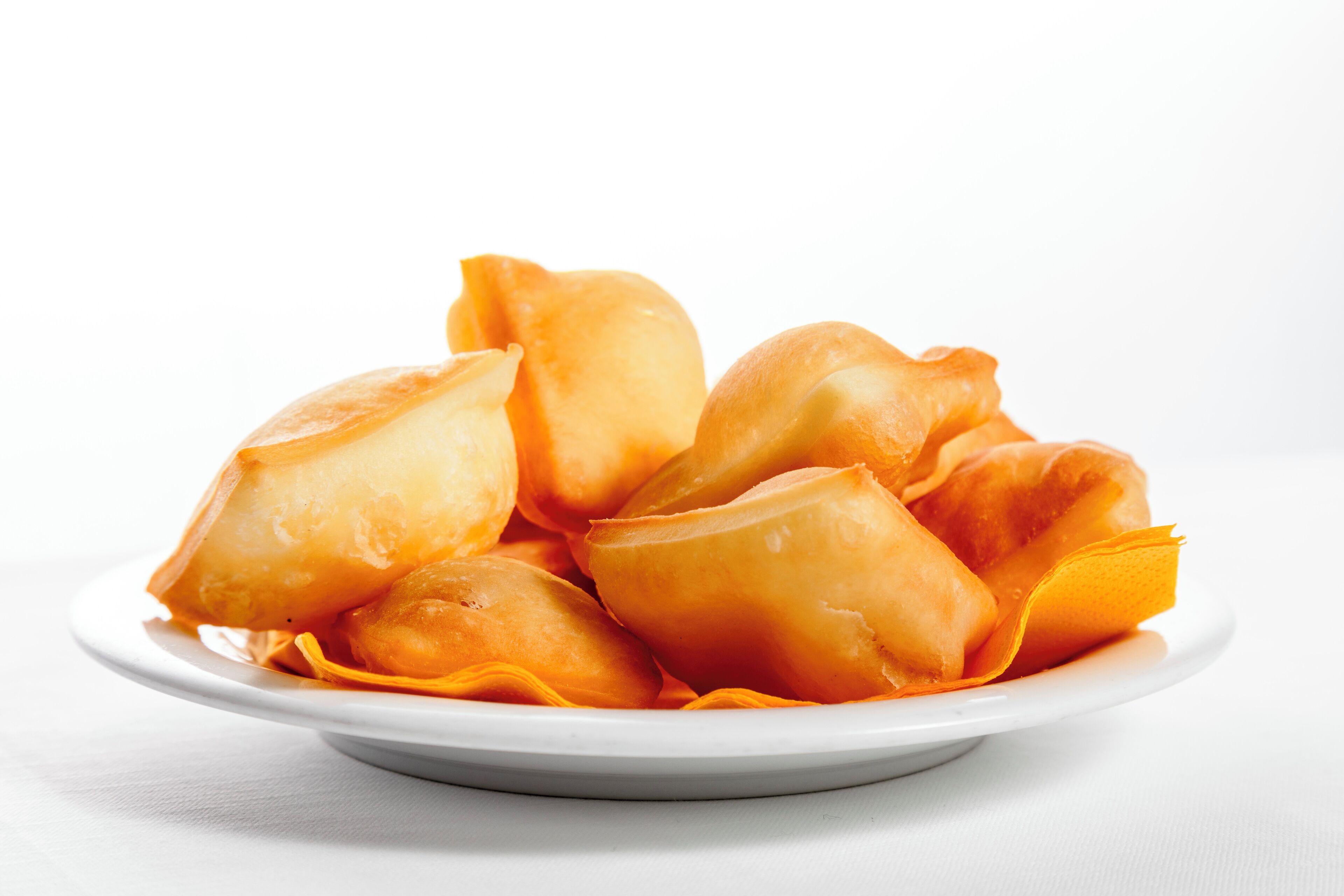 Un plato de pasteles dorados sobre una fuente blanca.