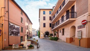 Una calle estrecha flanqueada por edificios, con una fuente en el centro y una señal de prohibido el paso a la derecha.