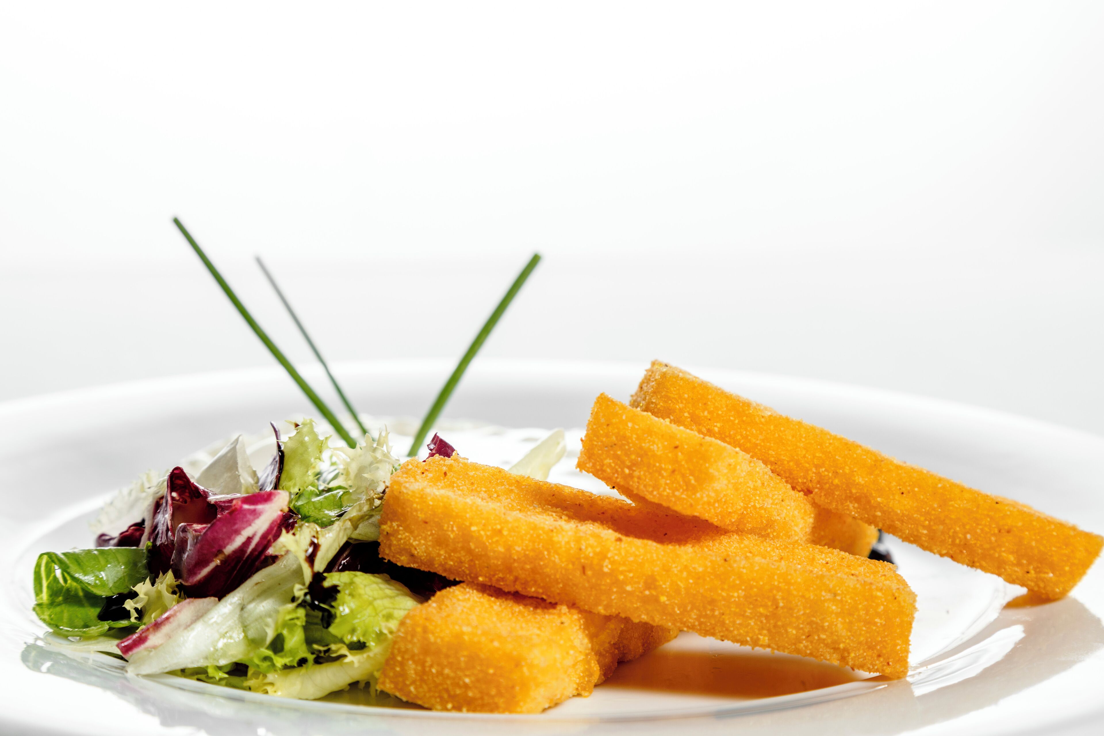 A plate with a salad and breadsticks.