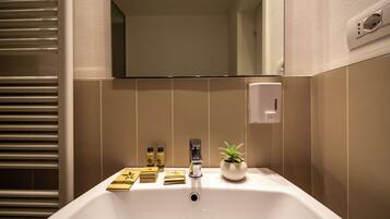 Un baño con lavamanos blanco, un espejo y una planta en maceta.