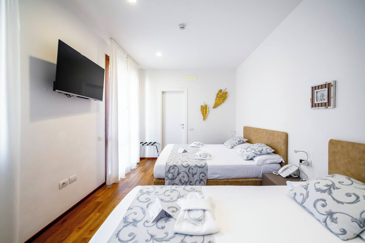 Una habitación de hotel con dos camas, un televisor y una puerta que da a un pasillo.