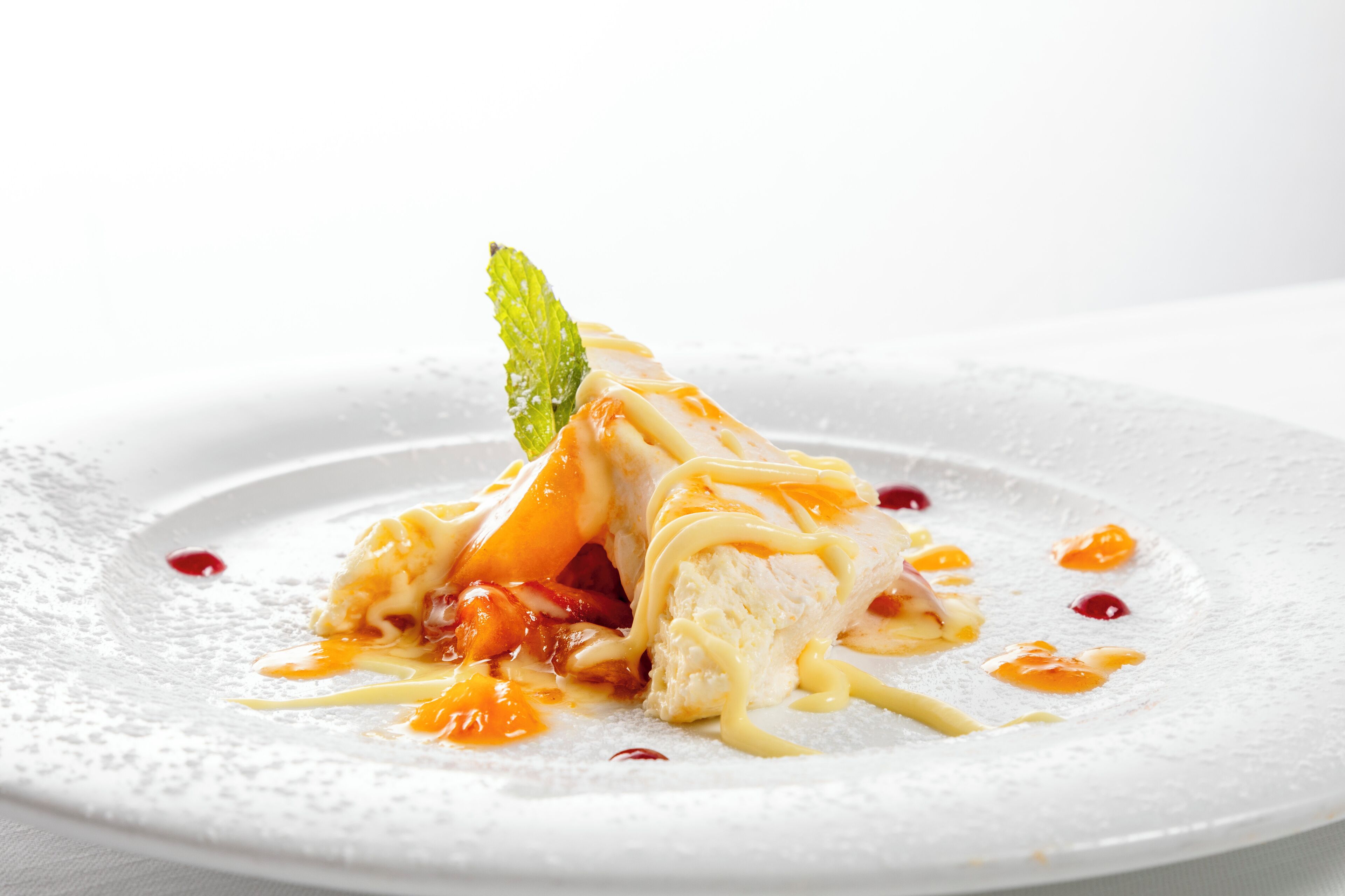 A dessert on a white plate with a mint leaf garnish.