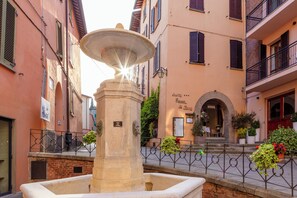 A fountain in a narrow street with buildings on either side. - Albergo La Rocca (Brisighella)