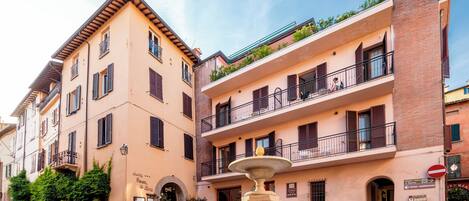 Un edificio histórico con una fuente al frente, varios balcones y un letrero que indica un restaurante.