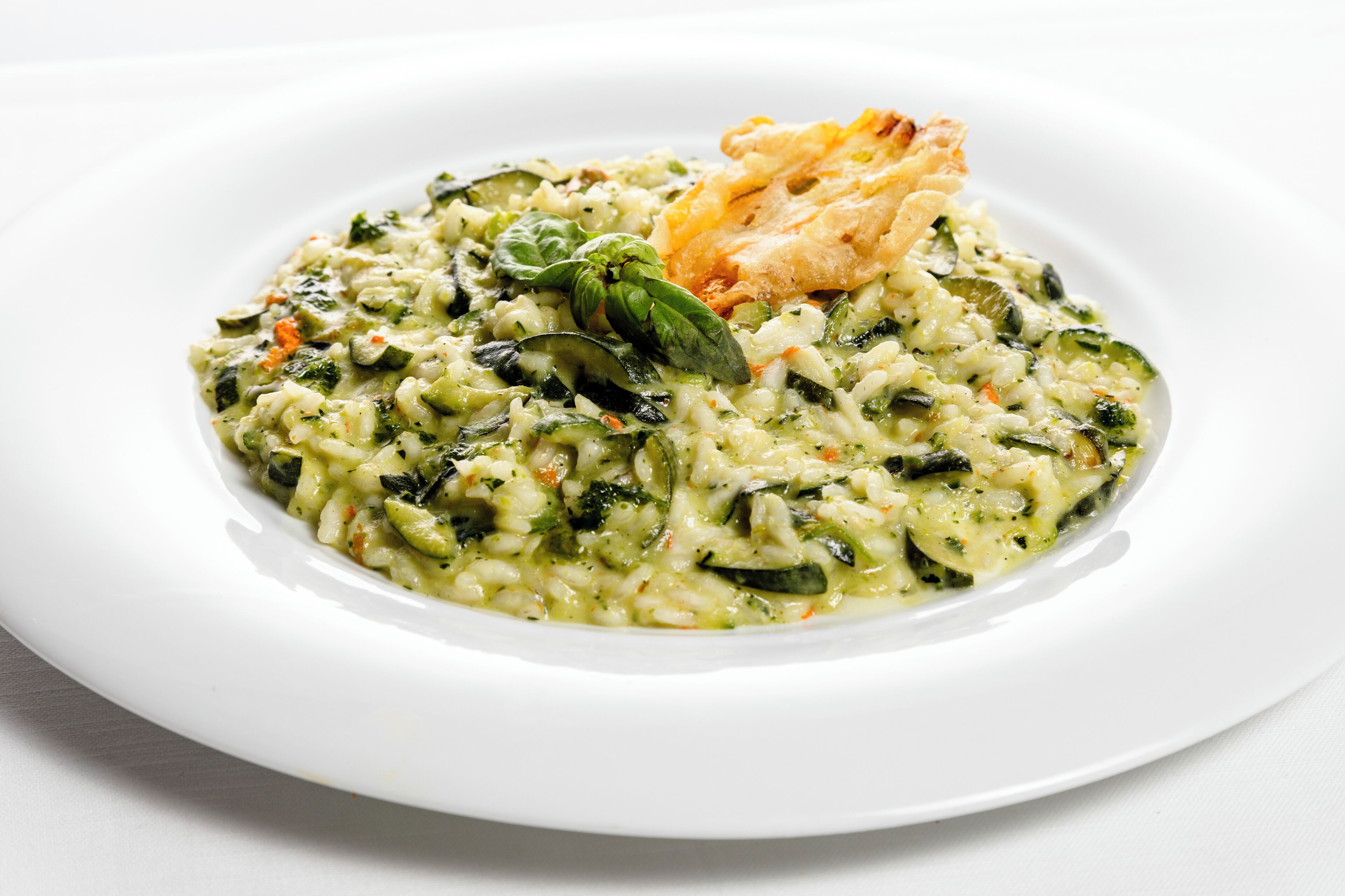 Un plato de risotto con vegetales y una rebanada de pan.