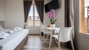 Una habitación de hotel con una cama, un escritorio con una silla, un televisor y una ventana con cortinas.