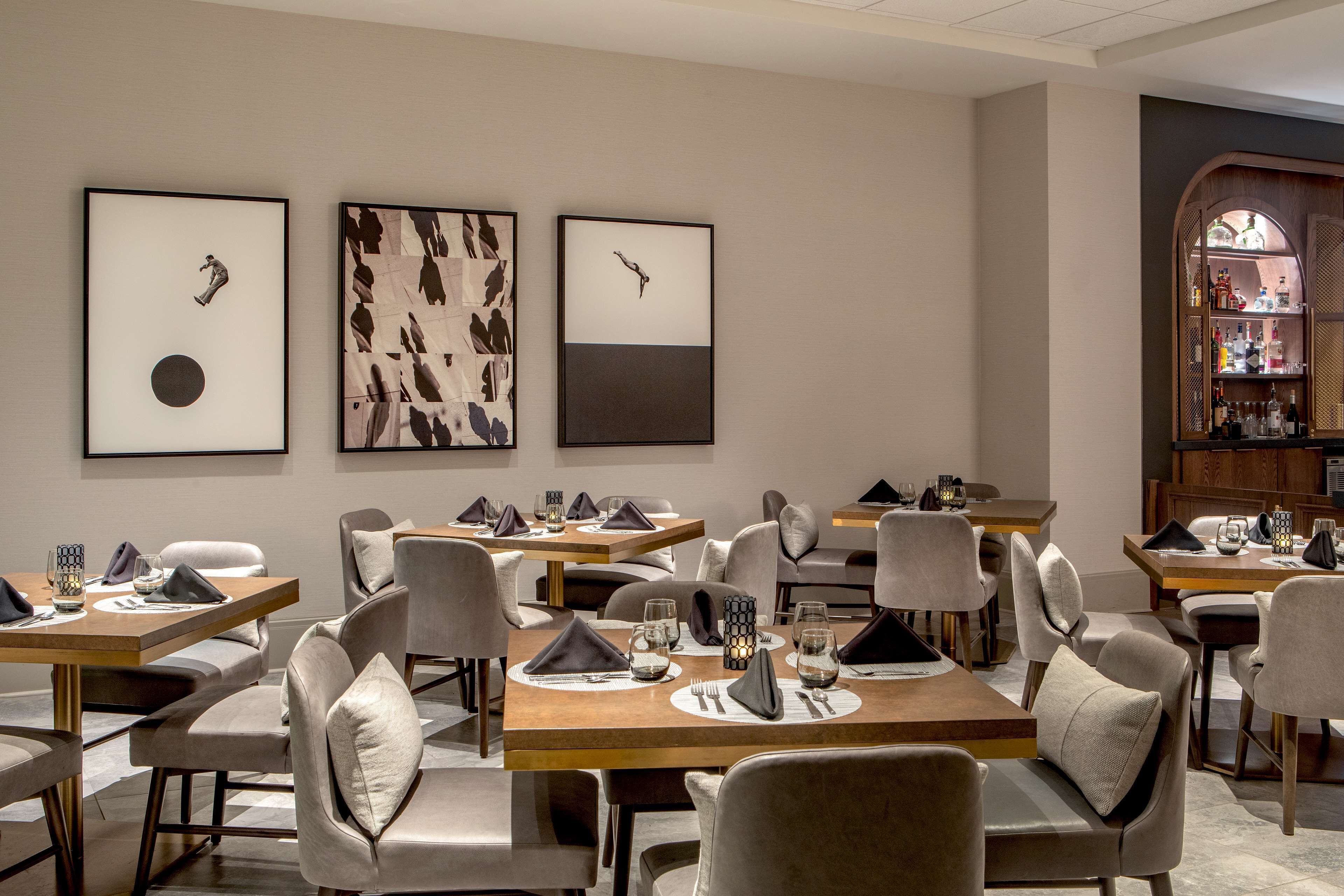 A dining area with multiple tables, chairs, and framed artwork on the walls.