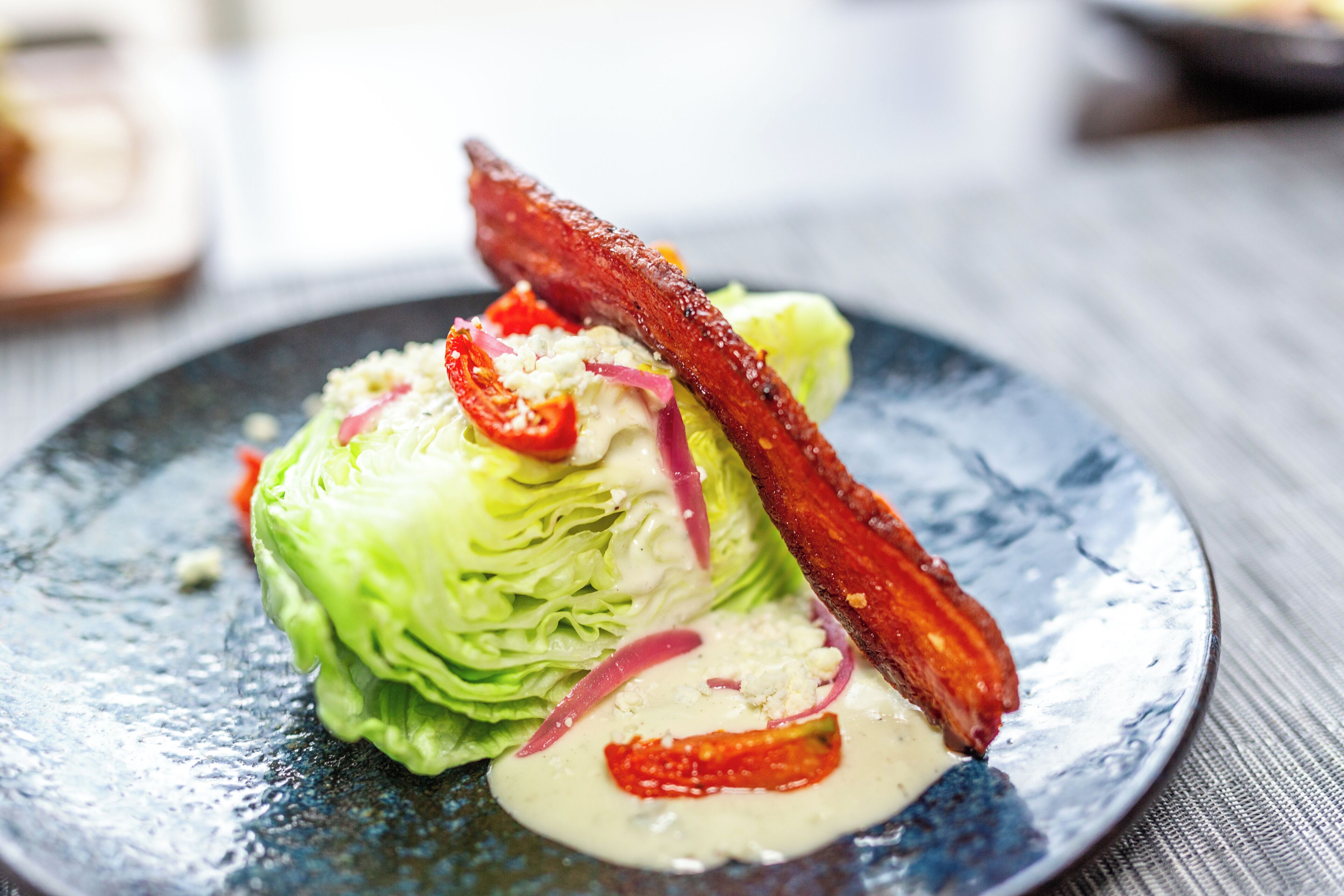 A plate with a salad, bacon, and a creamy sauce.