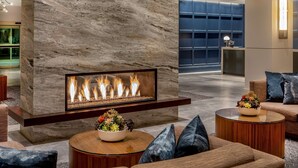A modern lobby with a stone fireplace, comfortable seating, and a reception area. - Hilton Columbus/Polaris (Columbus)