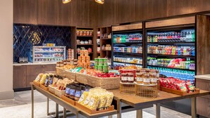 A grocery store interior with wooden walls, a central display table with snacks, and refrigerated sections on the right. - Hilton Columbus/Polaris (Columbus)
