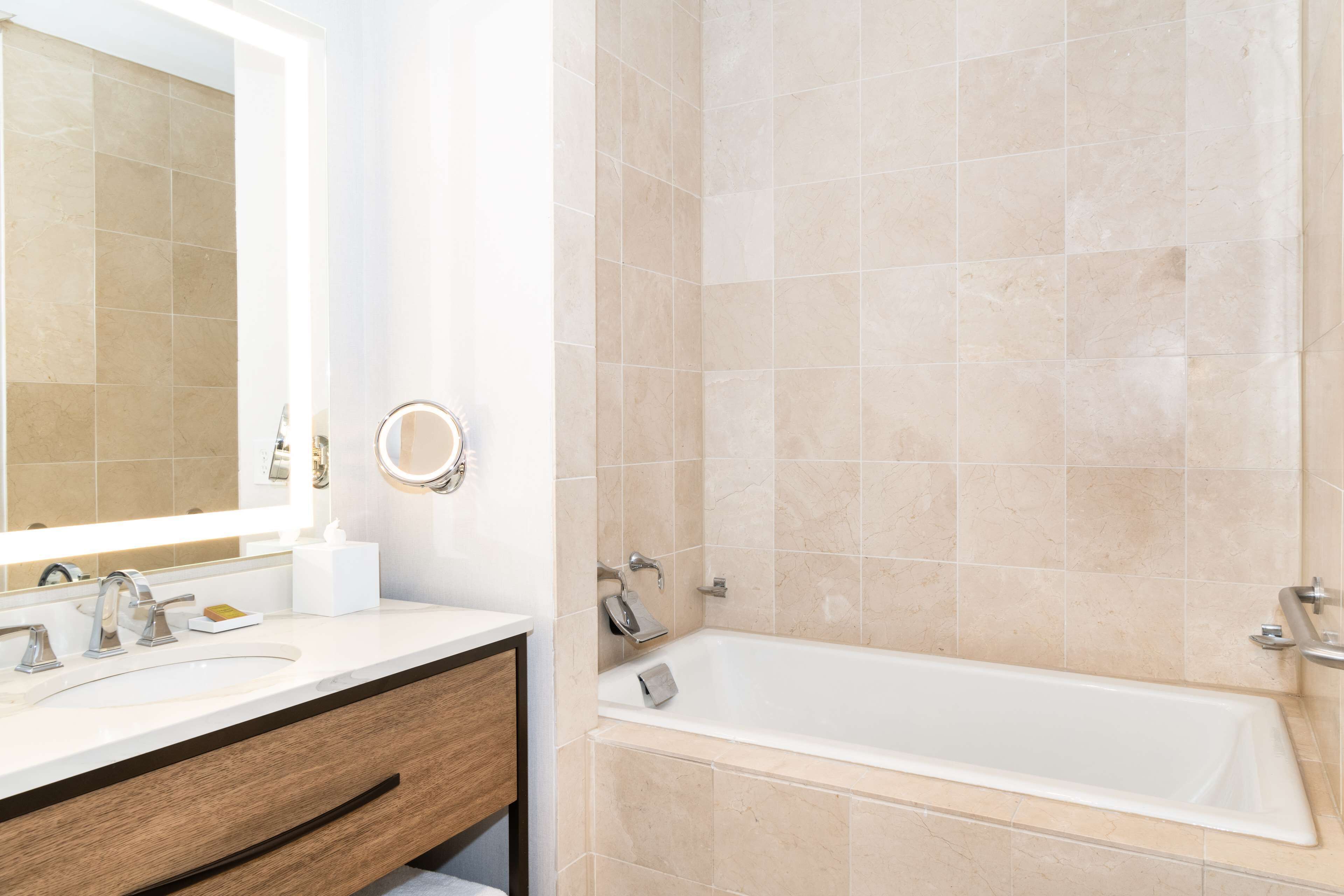 A bathroom with a sink, mirror, and bathtub.