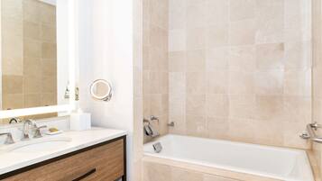 A bathroom with a sink, mirror, and bathtub.