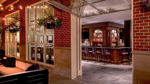 A bar area with a brick wall, hanging flower baskets, and bar stools. - Hilton Columbus/Polaris (Columbus)