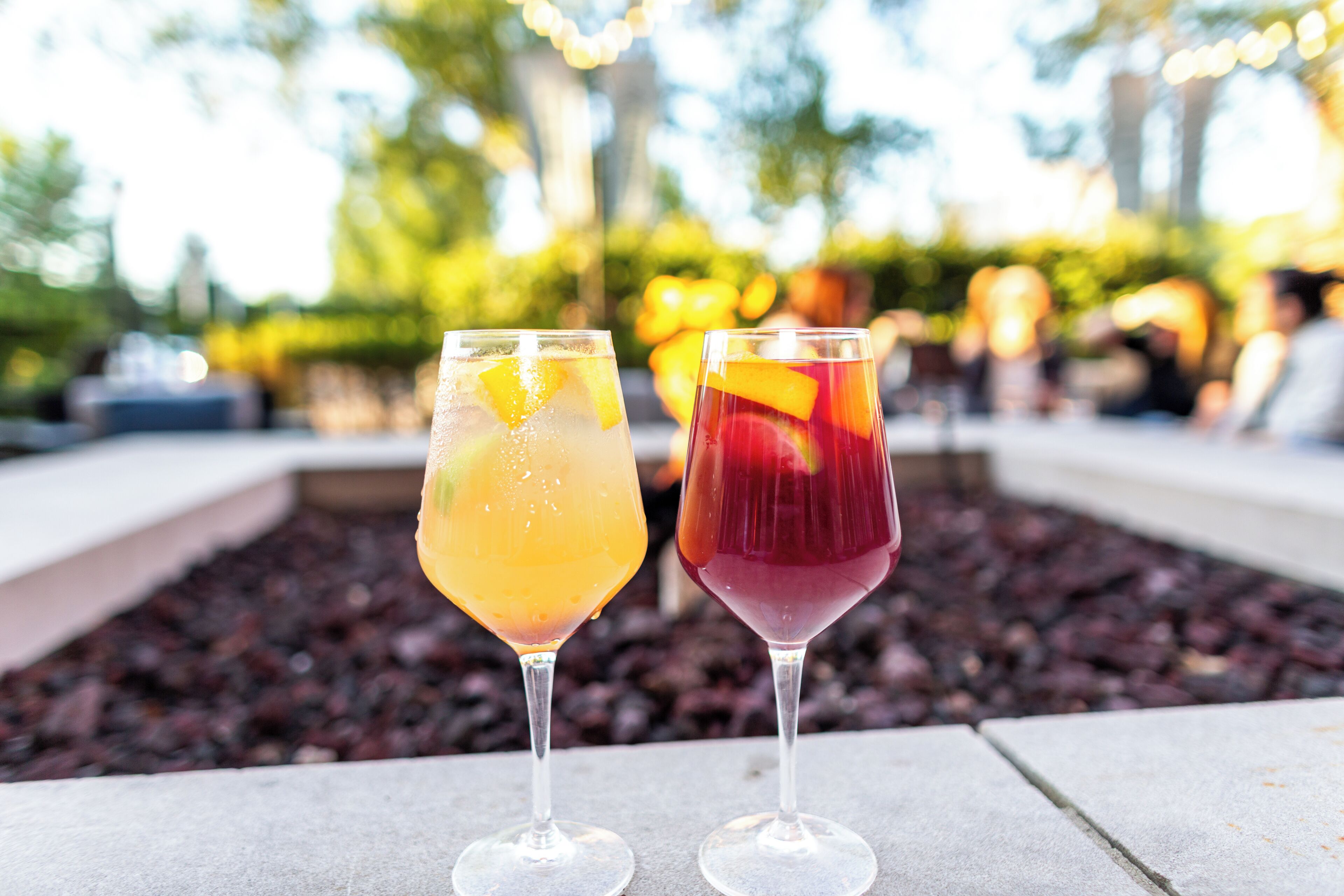 Deux verres de boissons posés sur une surface en pierre, avec un arrière-plan extérieur flou.