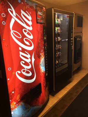 A vending machine with a Coca-Cola logo and a vending machine with a variety of snacks. - AmericInn by Wyndham Monmouth (Monmouth)