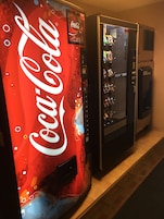 A vending machine with a Coca-Cola logo and a vending machine with a variety of snacks.