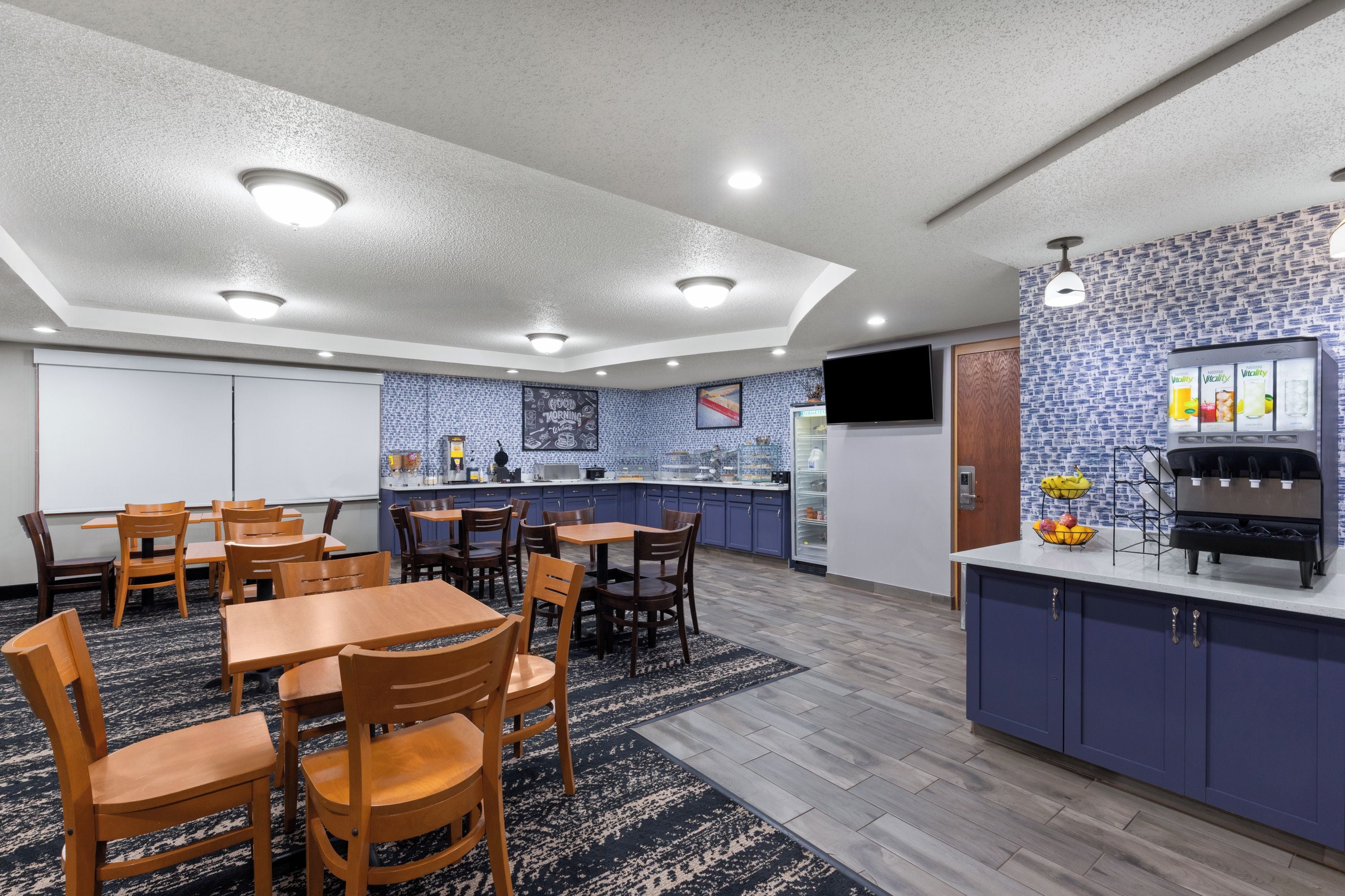 A modern kitchen with a blue backsplash, wooden tables, and chairs.