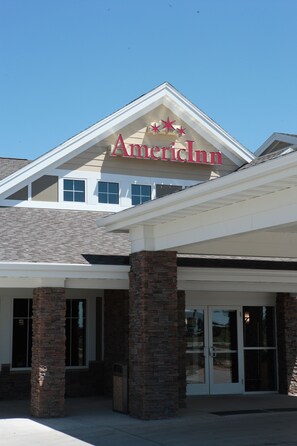 Exterior de un Inn americano con diseño moderno, que destaca un letrero prominente, pilares de ladrillo y amplias puertas de vidrio.