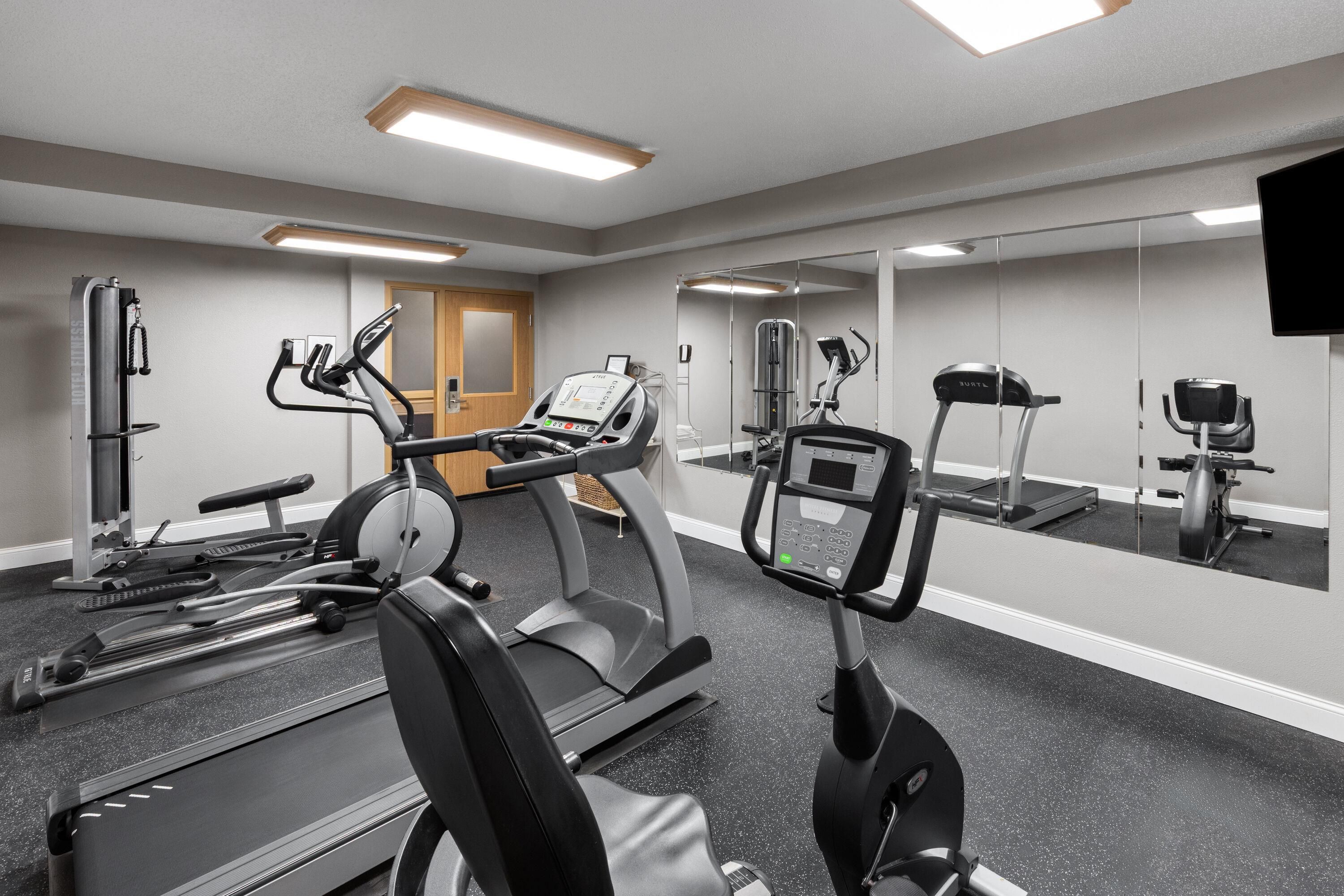 Ein Fitnessstudio mit Laufbändern, Crosstrainern und Kraftgeräten.
