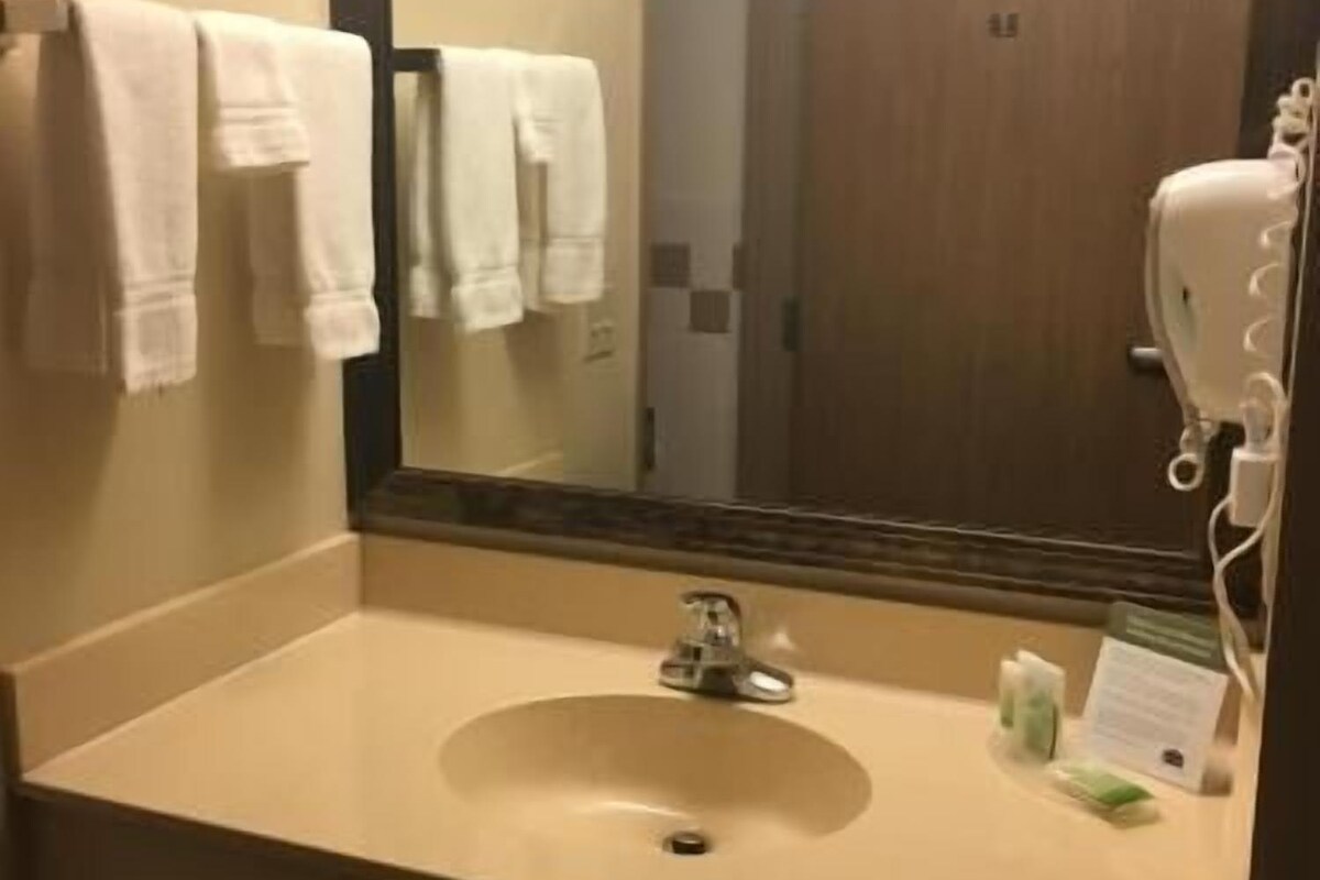 Un baño con lavamanos, espejo y perchero para toallas.