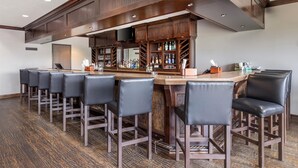 A bar area with multiple stools and a bar counter, featuring a wooden design and a flat-screen TV mounted above. - Best Western Plus Cimarron Hotel & Suites (Stillwater)