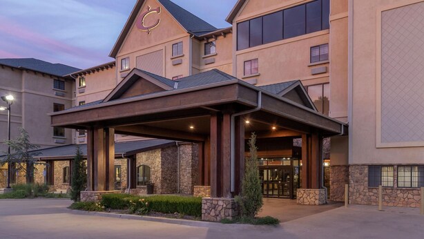 A hotel with a stone facade, a covered entrance, and a prominent logo on the building. - Best Western Plus Cimarron Hotel & Suites (Stillwater)