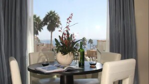 A dining area with a table, chairs, a vase with flowers, a bottle, and a book. - Aurora Hotel (Avalon)