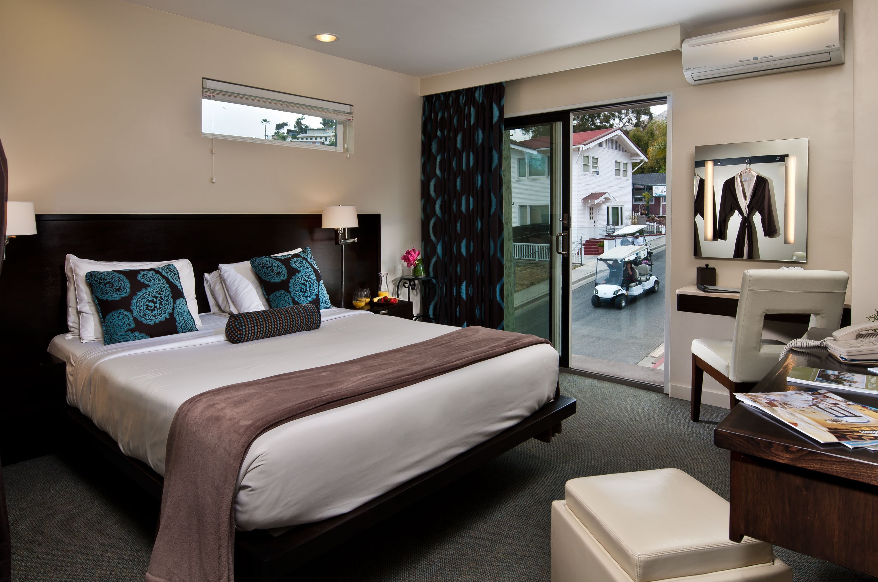 A hotel room with a large bed, a desk, a chair, and a view of the outside.