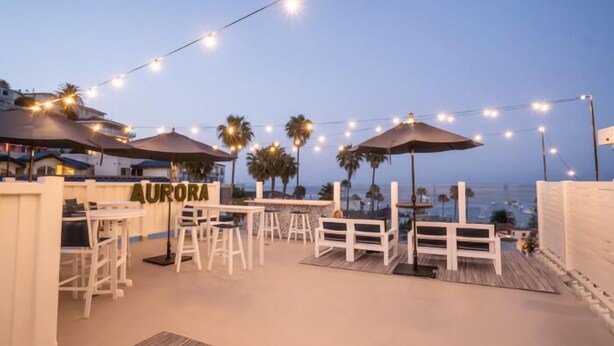An outdoor patio area with string lights, umbrellas, and seating. - Aurora Hotel (Avalon)