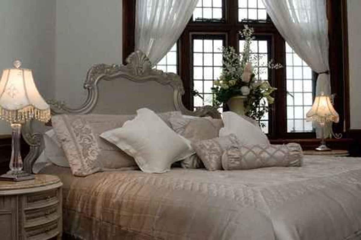 Une chambre à coucher avec un grand lit, une tête de lit décorée et deux lampes de chevet.