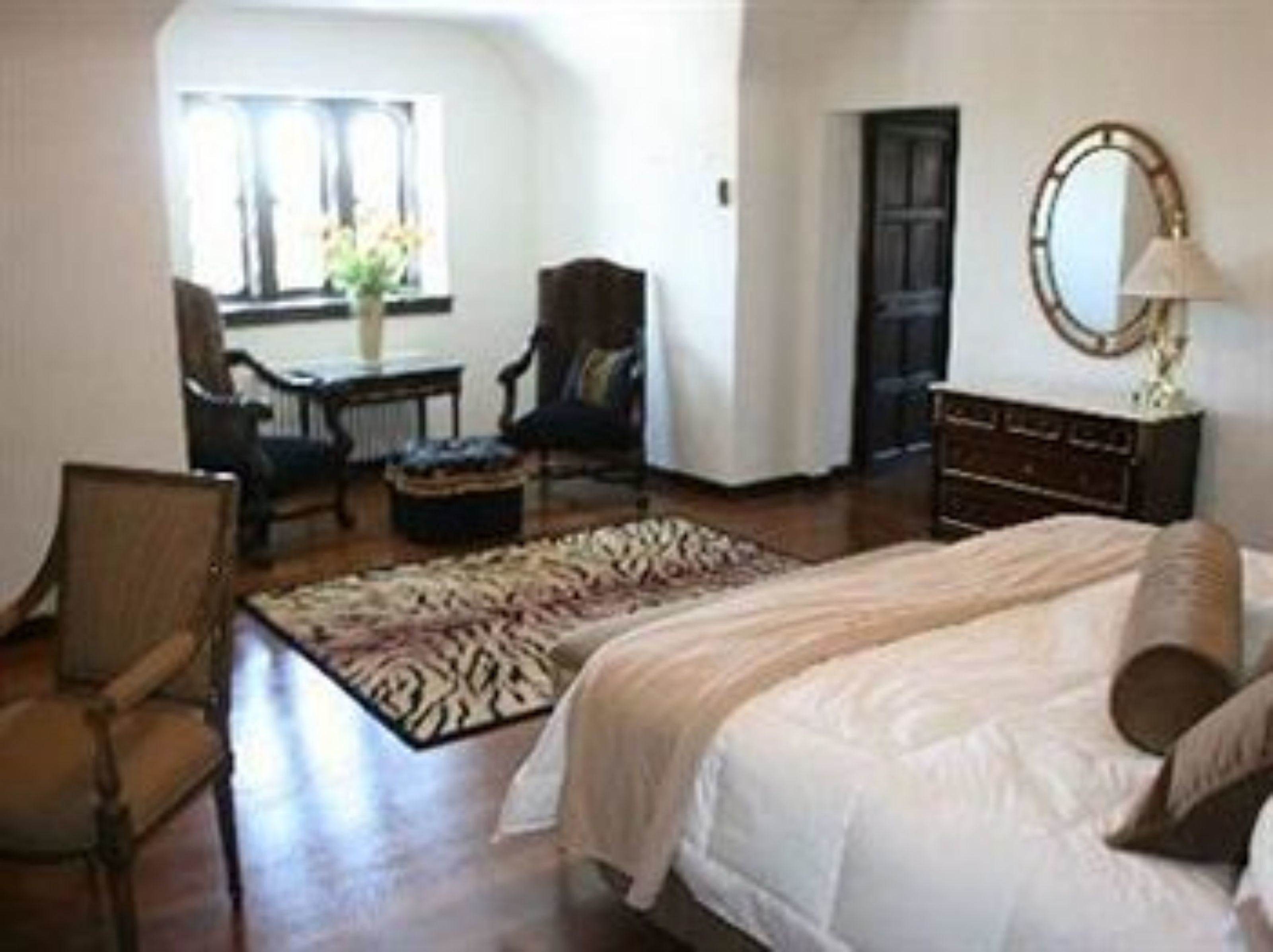 Une chambre à coucher avec un lit, une chaise, une commode et un miroir.