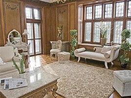 Um quarto amplo com uma grande janela, um sofá confortável, uma mesa de centro de mármore e um armário de madeira clássico.