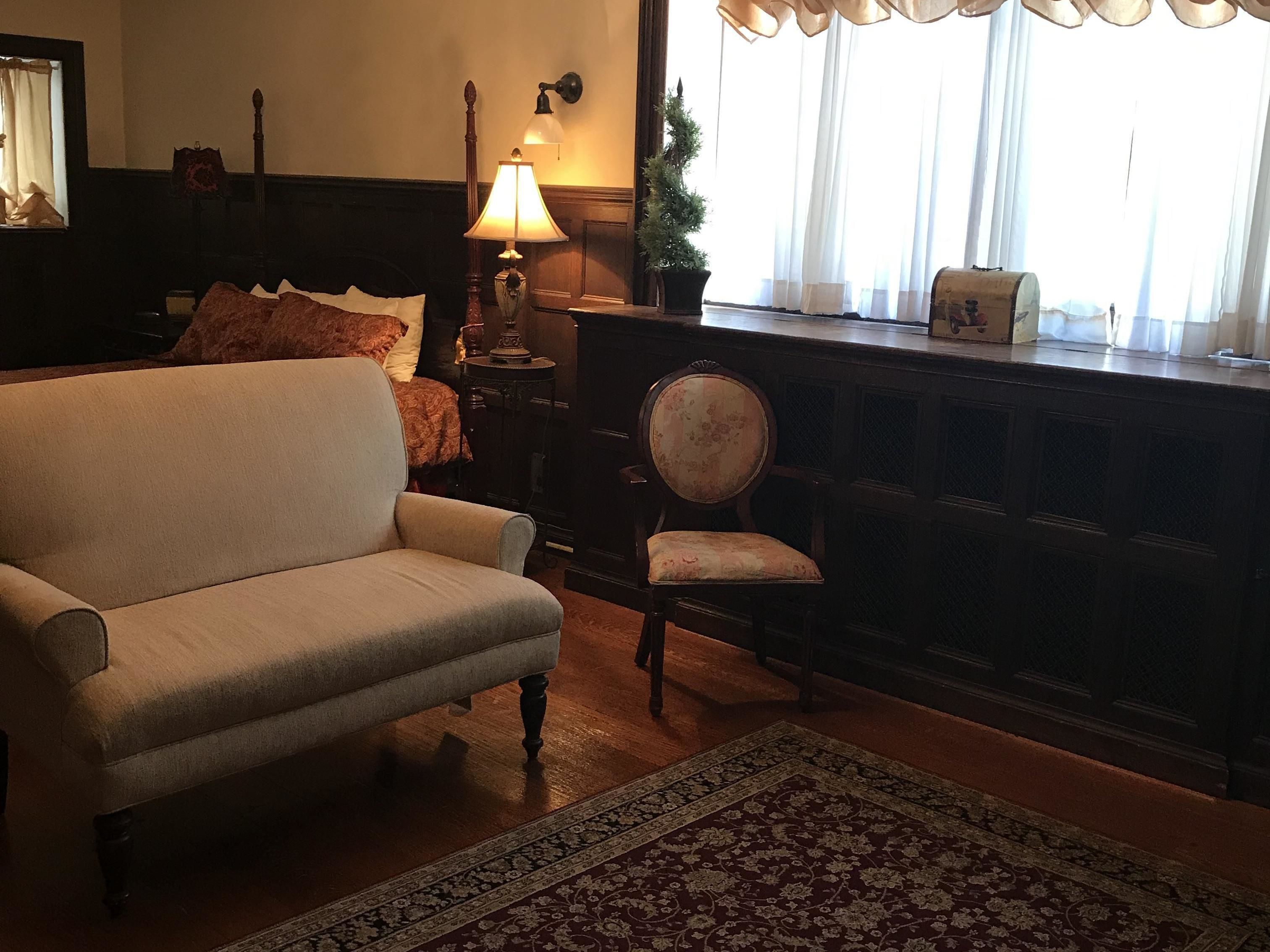 A traditional living room with a sofa, a chair, a lamp, and a small table with a decorative item.