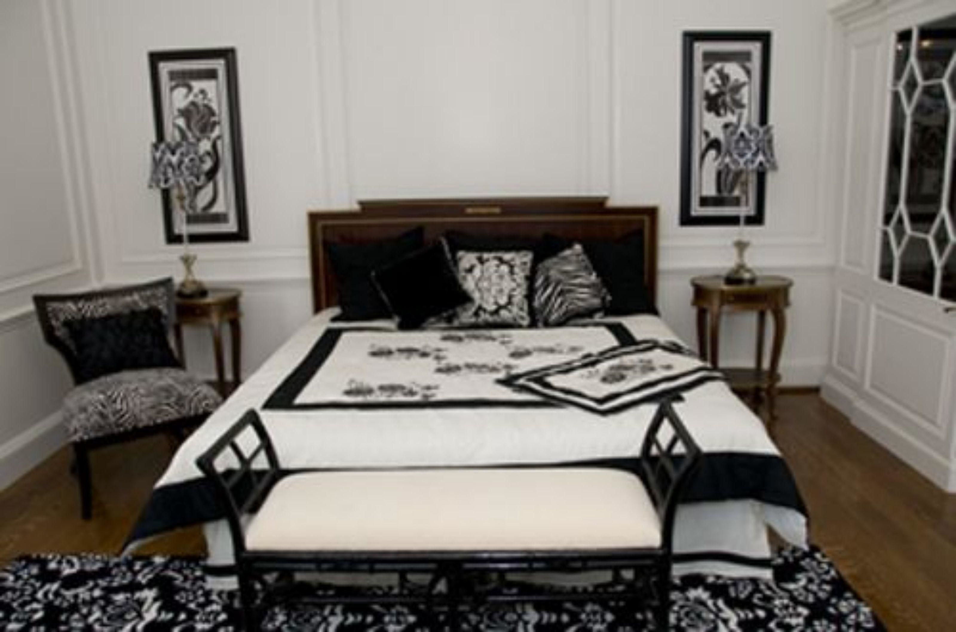 A bedroom with a large bed, two bedside tables, a chair, and framed artwork on the walls.